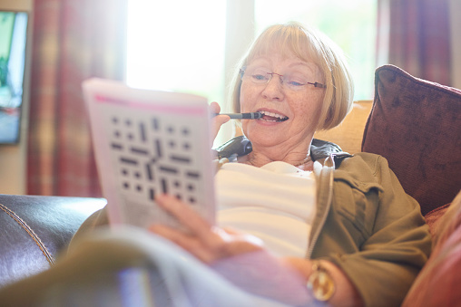 senior woman doing crossword puzzle at home