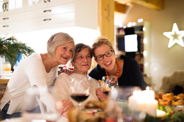 Mother, grandmother and daughter celebrating Christmas. Beautiful big family sitting at the table celebrating Christmas together at home. Mother, gradmother and daughter drinking red wine. multi generation family christmas stock pictures, royalty-free photos & images