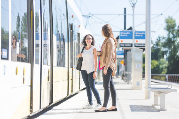 istock Female friends commuting on train wait on station platform together 851276576