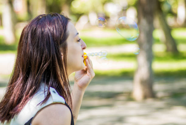 istock caucasian woman blowing soap bubbles in the park 851349586
