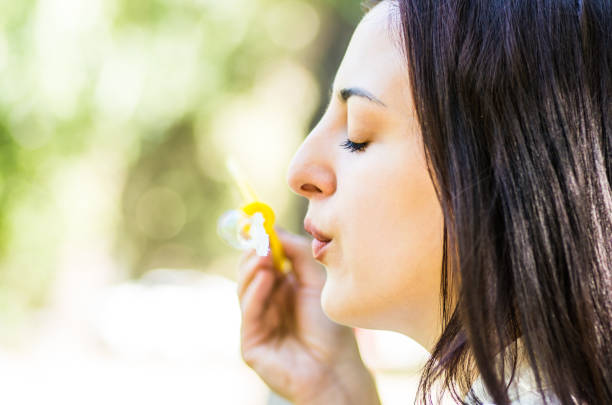 istock caucasian woman blowing soap bubbles in the park 851350636