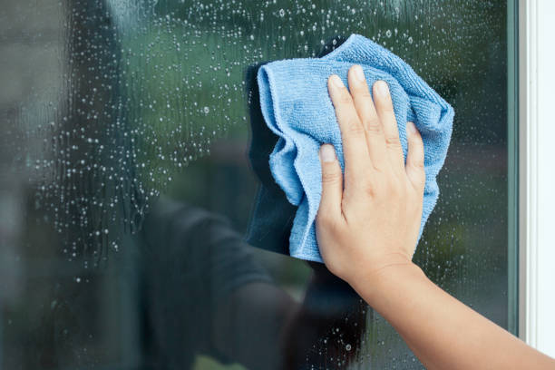 Woman hand cleaning window with rag stock photo