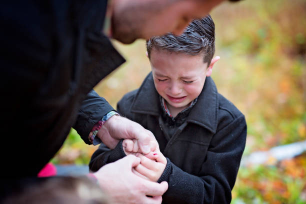istock Small boy crying in pain injuring his hand. Father provides first aid 851435636
