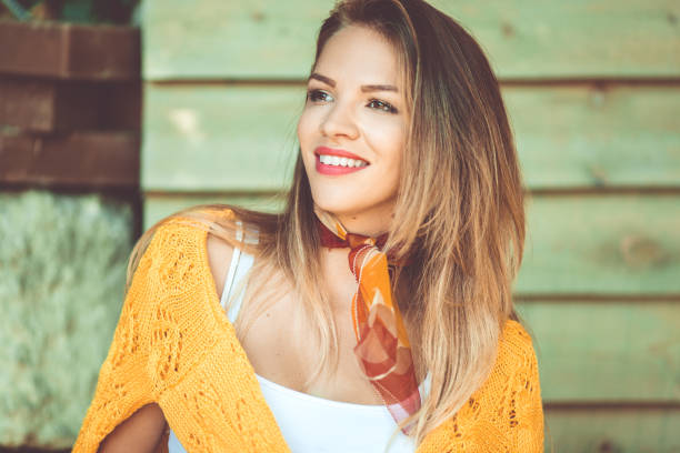 Fashion smiling woman is wearing yellow sweater over wooden background stock photo