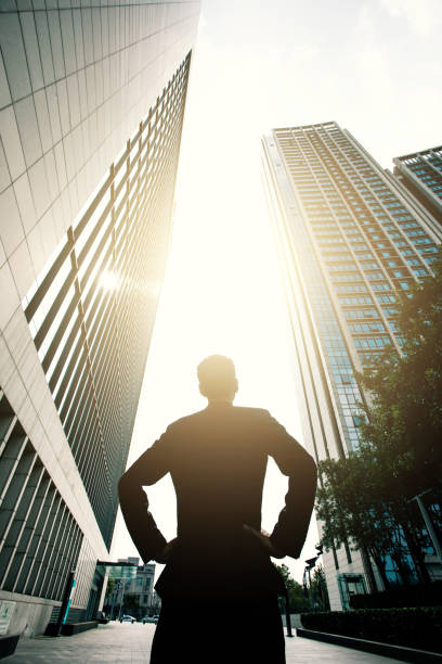 istock Businessman standing between city buildings 851475824