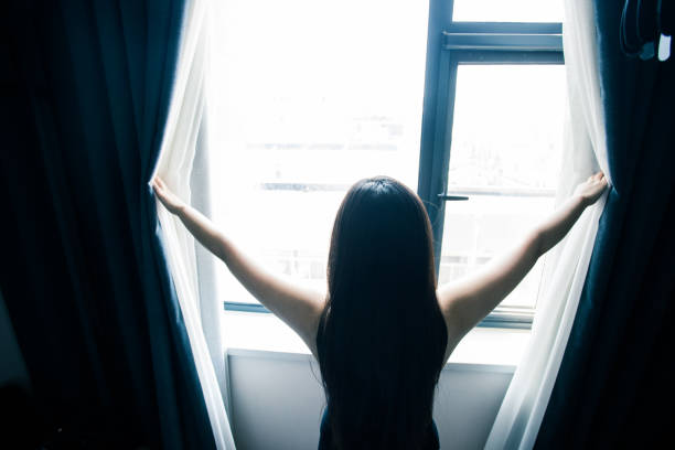 istock young woman open the curtains 851478922