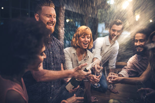 homme rousse ouvrant un champagne sur une fête avec ses amis. - soirée arrosée photos et images de collection