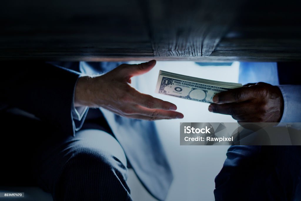 Hands passing money under table corruption bribery Bribing Stock Photo