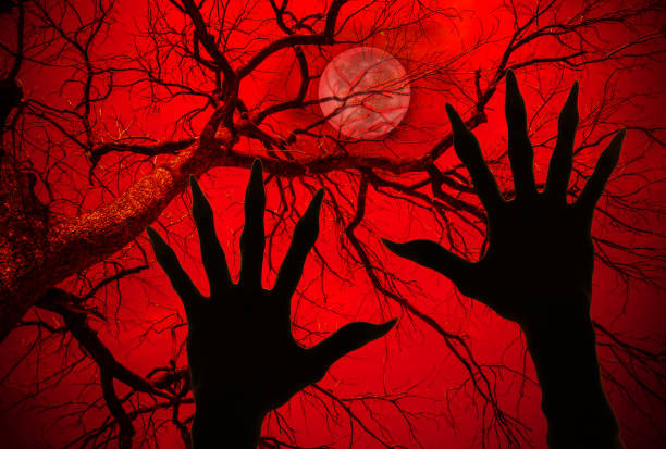 istock Halloween concept, zombie lifts hands up on dried branches background 851502106