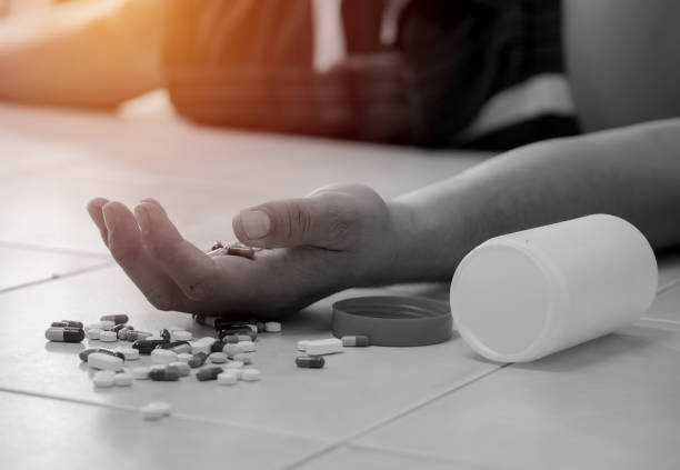 Overdose - close up of pills and addict lying on the floor Overdose - close up of pills and addict lying on the floor drug overdose stock pictures, royalty-free photos & images