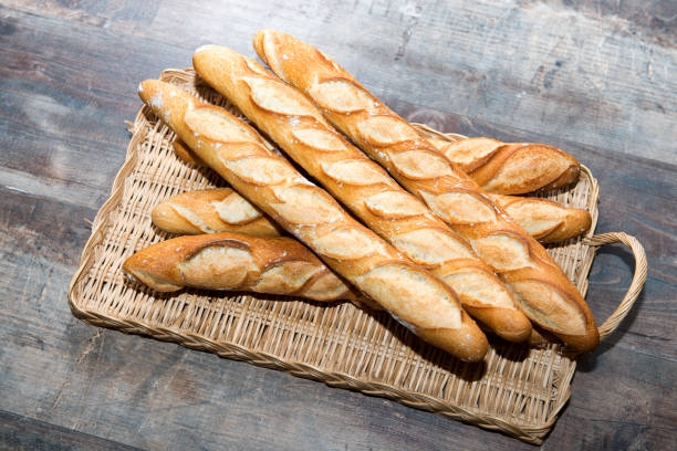 bastone di pane francese su un tavolo rustico - baguette foto e immagini stock