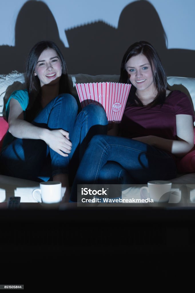 Foto de Dois Amigos Sorridentes No Sofá Assistindo Tv Juntos No Escuro e  mais fotos de stock de Assistir TV - iStock