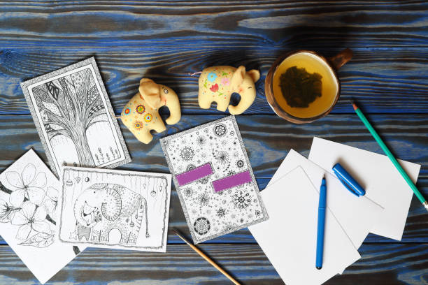Many postcard in doodling style with drawn picture, pencils, pen and ceramic cup with tea lemon and two fabric toy small elephants on wooden blue background. Hand drawn, creativity, humor, ideas. Top view. Place for inscription. Copy space muchos postal garabatos estilo imagen dibujada, lápices, pluma y taza de cerámica con limón té y dos elefantes pequeños de juguete de tela en fondo azul madera. dibujado a mano, creatividad, humor, ideas. vista superior. lugar de inscripción. copia espacio