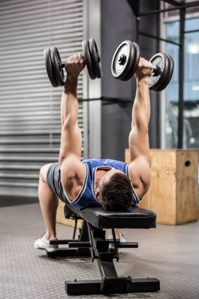 istock Muscular man on bench lifting dumbbells 851520932