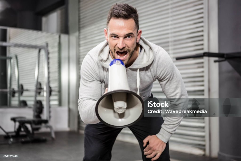 Muscular man shouting on megaphone Muscular man shouting on megaphone at the gym gym Fitness Instructor Stock Photo