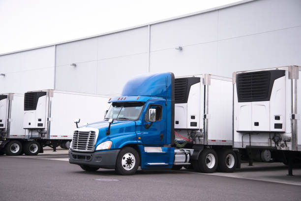 istock Big rig day cab semi truck and reefer trailers with refrigerator units loading cargo from warehouse building 851543360