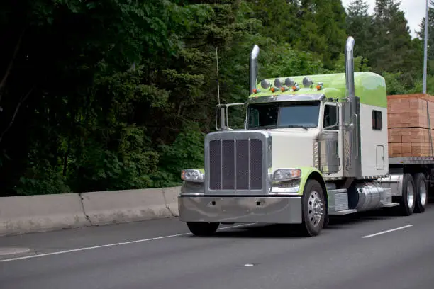 Photo of Big rig classic semi truck with flat bed trailer trancport lumber wood