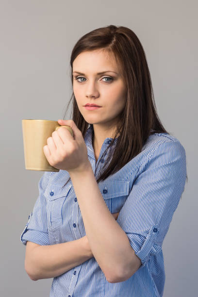 istock Serious pretty brunette holding cup of coffee 851544078