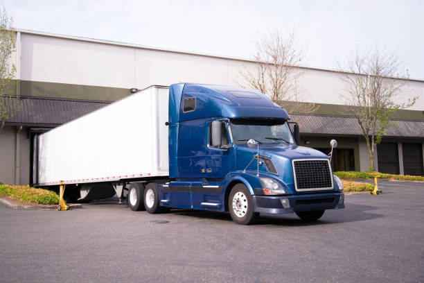 istock Dark blue big rig semi truck with trailer in warehouse dock loading commercial cargo 851548664