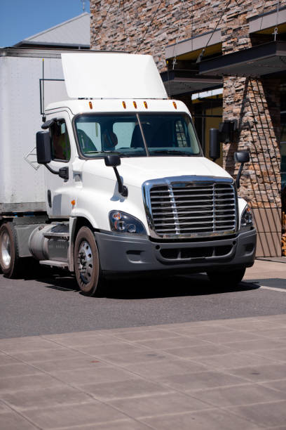 istock Day cab delivery semi truck with dry van trailer unloading cargo to retailer store 851548996