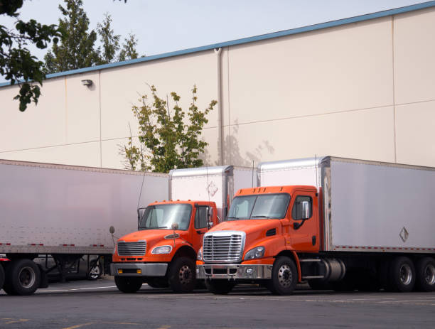 istock Orange midlle semi trucks with box trailers stand in warehouse dock under unloading 851551898