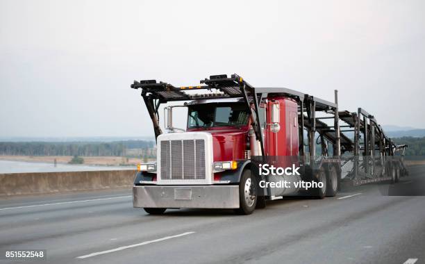 Photo libre de droit de Classique Rouge Big Rig Camion Semi Avec Voitureremorque Transporteur Exécutant En Route Au Point De Chargement Des Voitures Pour La Livraison banque d'images et plus d'images libres de droit de Transport