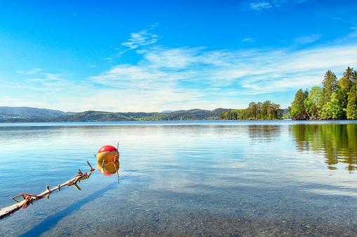 Lake Jonsvatnet located near the norwegian city Trondheim in the sunny summer day. Red float reflected in the water.