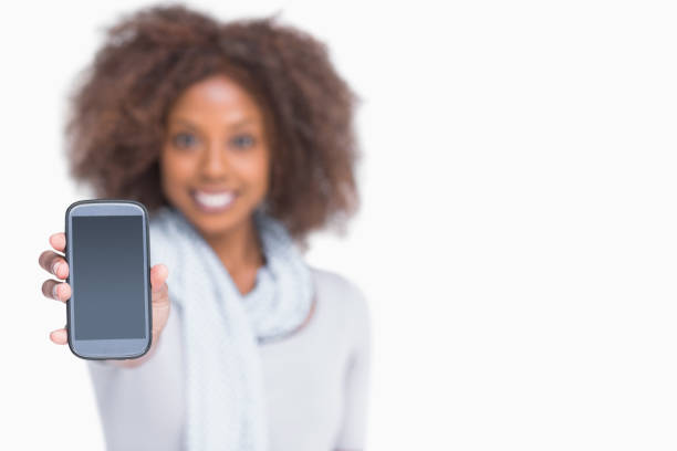 Woman with afro showing her smartphone to camera on white background
