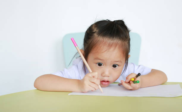 istock Asian child in school uniform with pencil writing on table isolated on white background. 851573434
