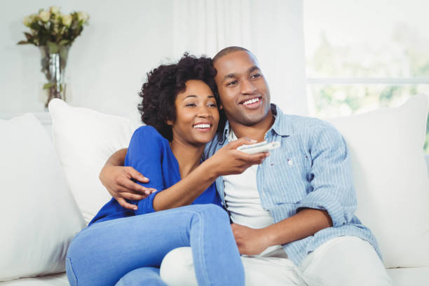 istock happy couple watching television on the sofa 851585126