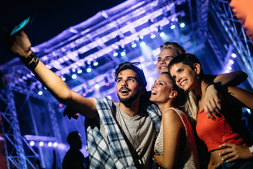 Happy young friends taking selfie at music festival