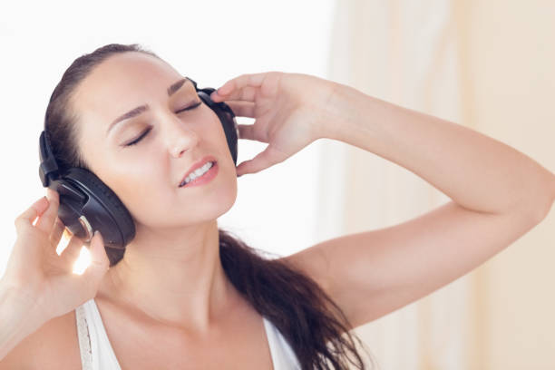 istock Relaxed brunette sitting on bed listening to music 851590310