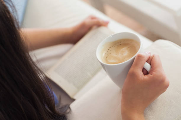 istock Woman lying on the sofa reading a book holding her coffee 851606390