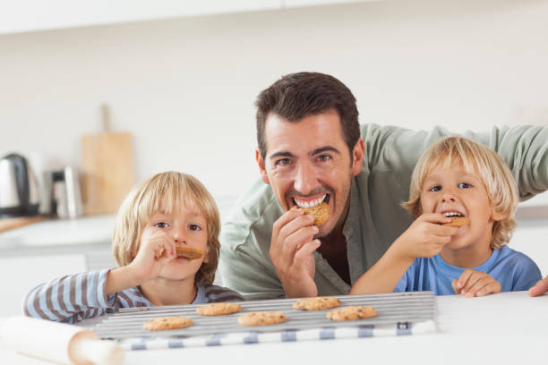 istock Smiling father and his sons eating cookies 851615160