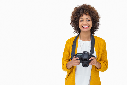 Pretty girl holding a camera on white background