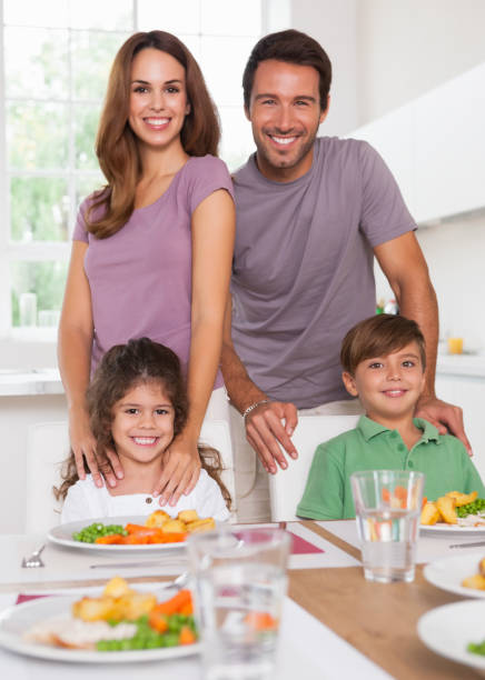 istock Two children and their parents smiling at the camera at dinner table 851675432