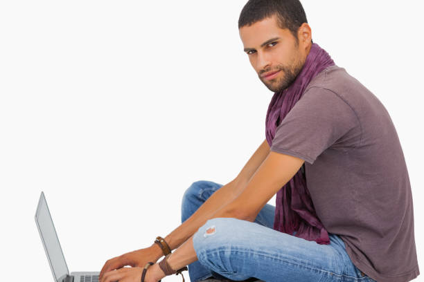 istock Serious man wearing scarf sitting on floor using laptop 851679936