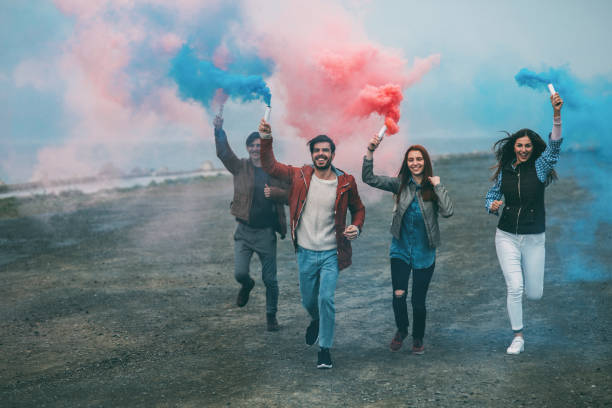 Friends running with smoke bombs in their hands