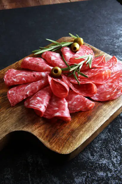 thinly sliced salami on a wooden cuttingboard