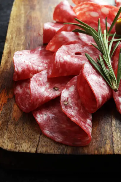 thinly sliced salami on a wooden cuttingboard