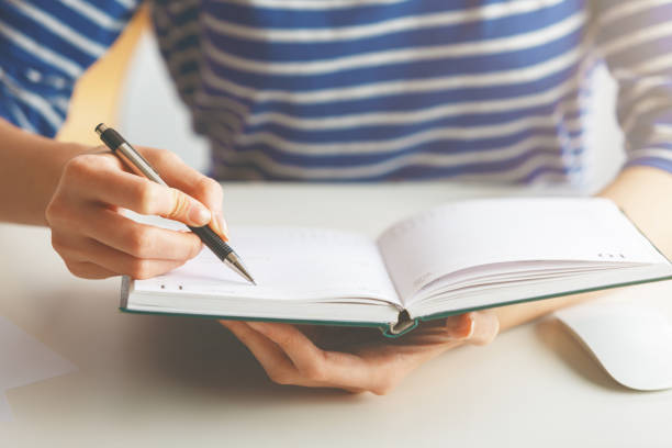 istock Woman writing in hardcover diary 851763146