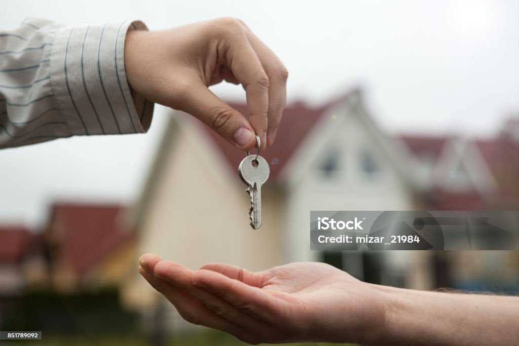 hand of a man handing keys to a man's hand Apartment Stock Photo
