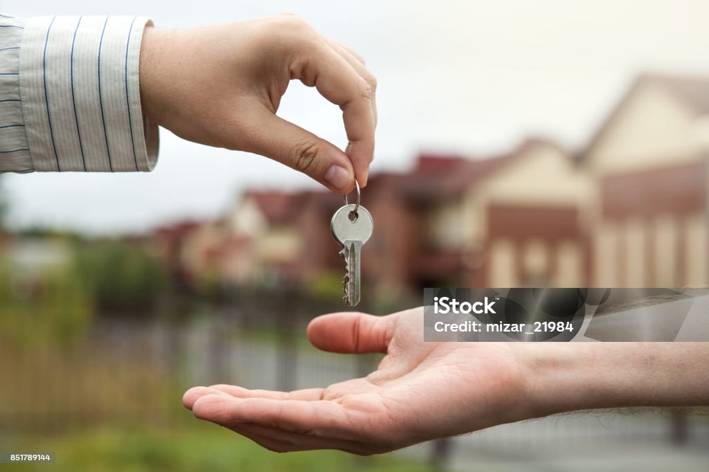 hand of a man handing keys to a man's hand Apartment Stock Photo