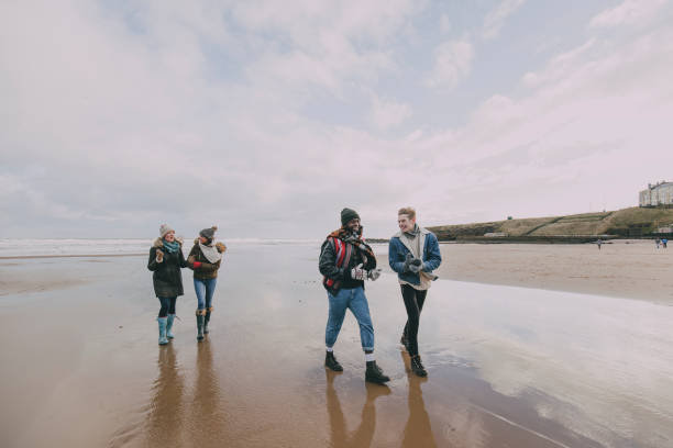 A Group Of Friends Walk Along A Winter Beach