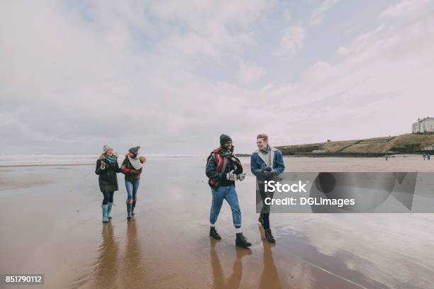 A Group Of Friends Walk Along A Winter Beach Stock Photo - Download Image Now - UK, Beach, Talking