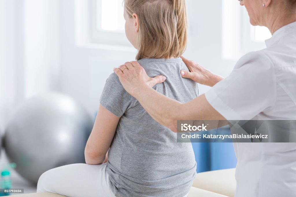 Physiotherapist doing massage to girl Physiotherapist doing massage to girl with spine defect during session in rehabilitation room Child Stock Photo