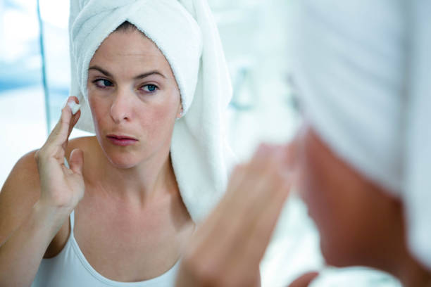 istock woman applying face cream in the mirror 851794586