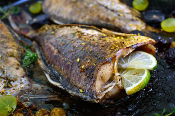 istock Baked carp with grapes, lime and herbs on black. 851800458