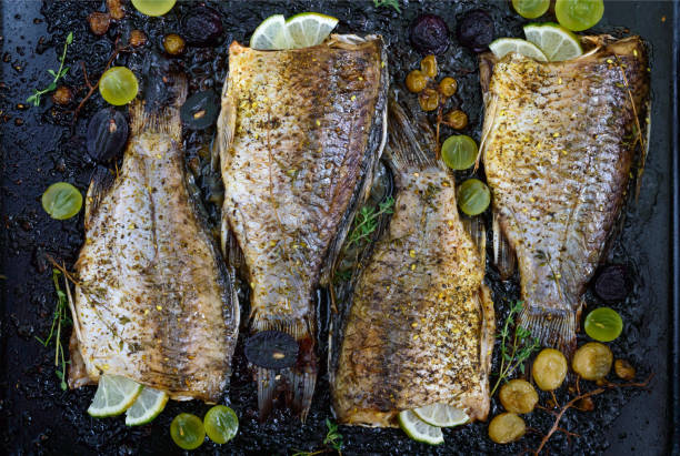 istock Baked carp with grapes, lime and herbs on black. 851800504