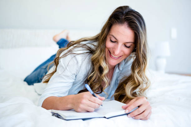 istock woman lying on her bed writing in a book 851802916